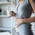 Slim,Woman,With,Stomach,Ache,And,Pain,Holding,A,Glass