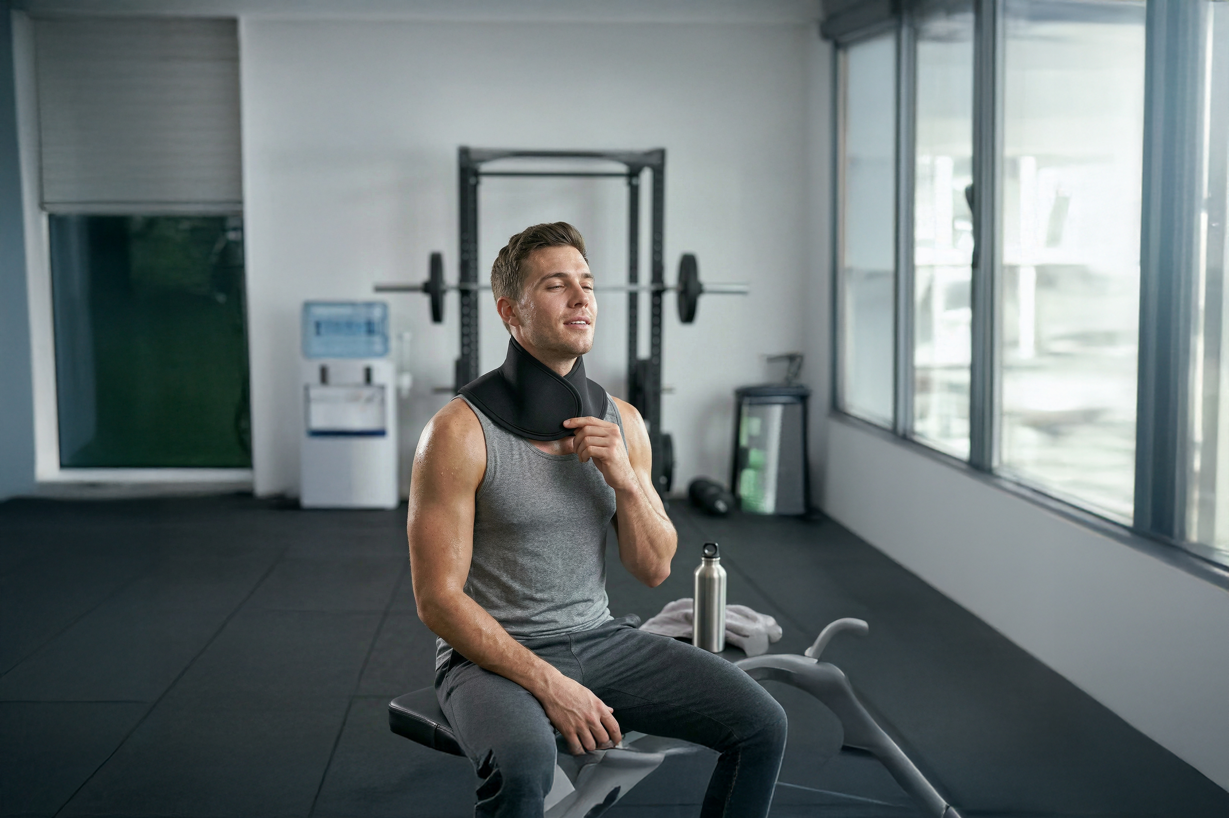 A man in a bright gym adjusting a medisana neck gel pack after training