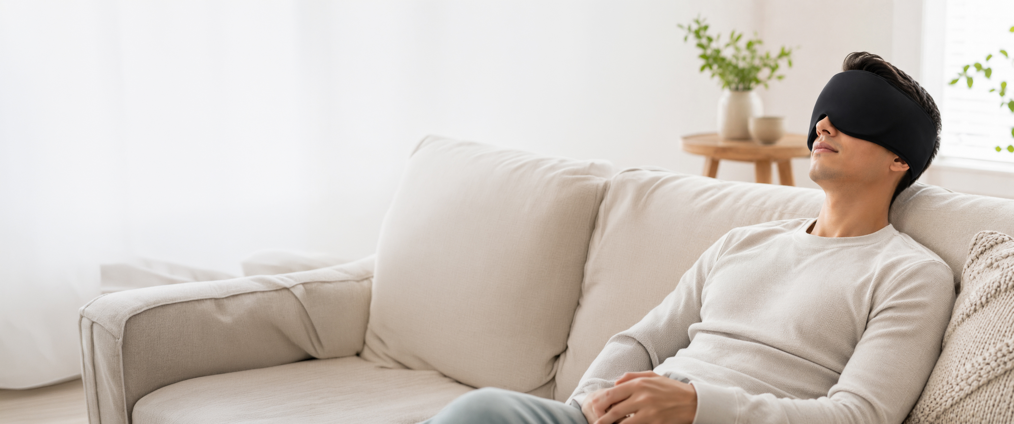 A man relaxing on a sofa wearing a medisana head gel pack over his eyes