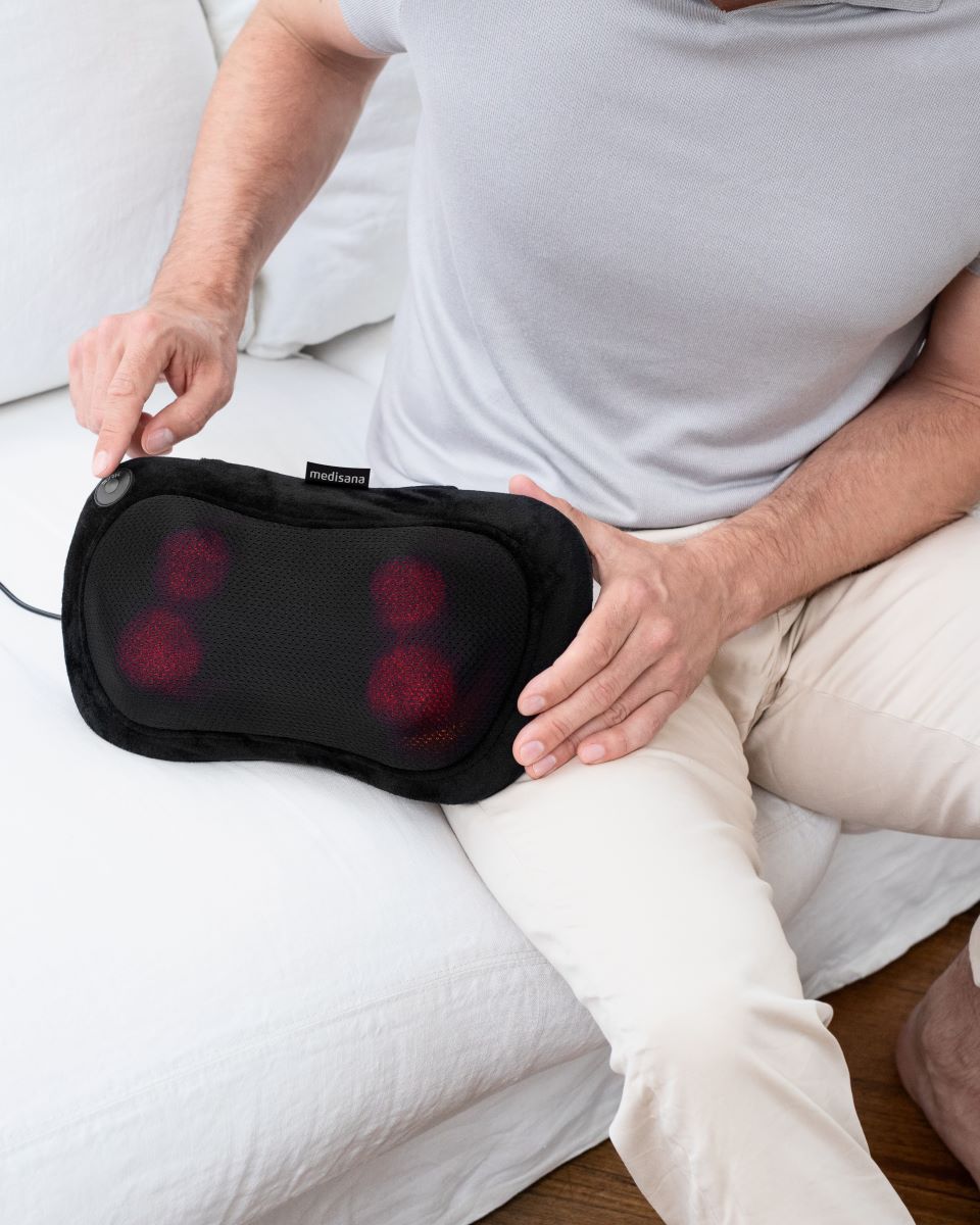 A person uses a Medisana massage cushion on the thigh for targeted muscle relaxation.