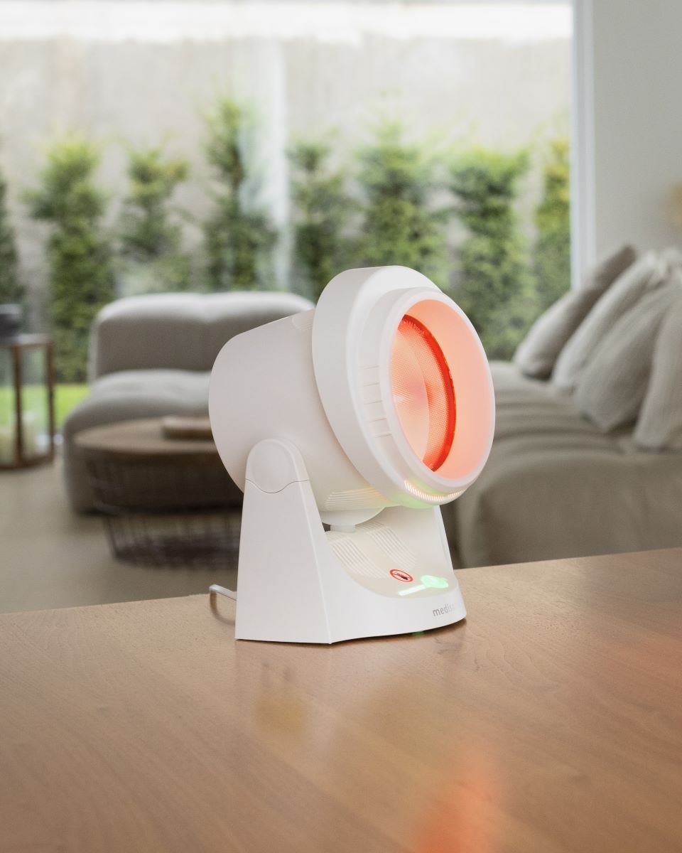 Medisana infrared lamp placed on a table in a living room with the heat lamp switched on