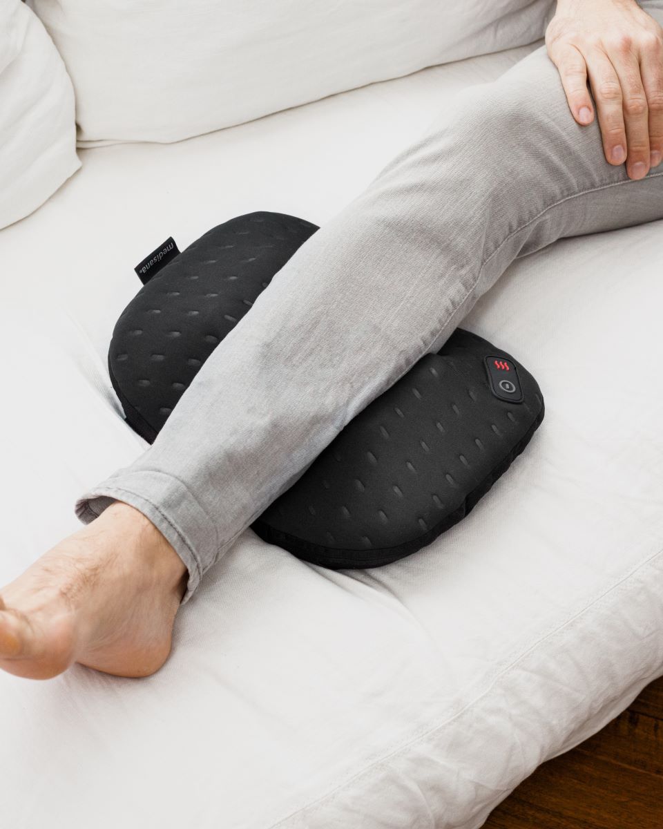 A person massages the calves with a Medisana massage cushion for focused muscle relief.